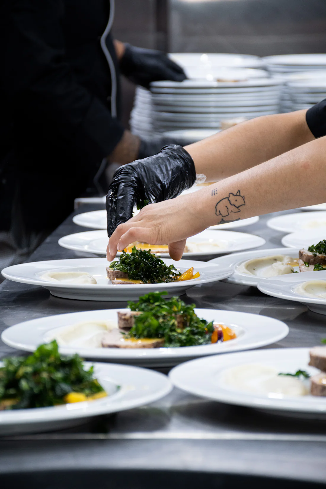 A cook plating freshly prepared meals by hand